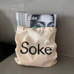 Soke tote bag styled with Soke Eye Treatments box and glass water bottle on counter, lifestyle product image.