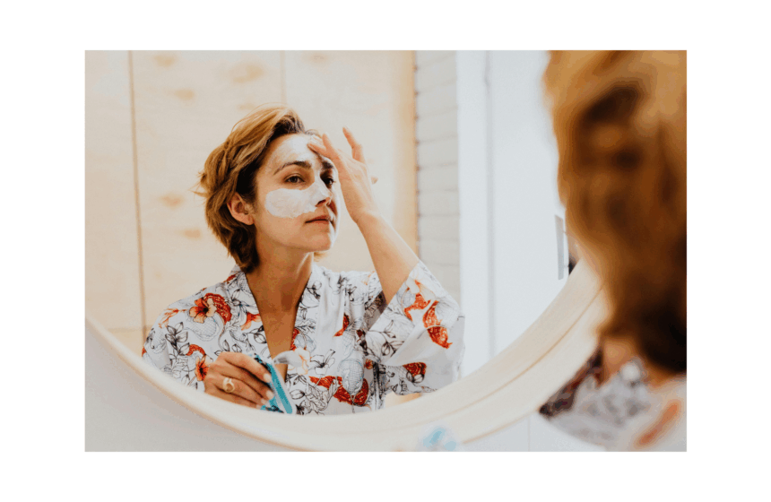 Woman applying skincare mask in front of mirror.